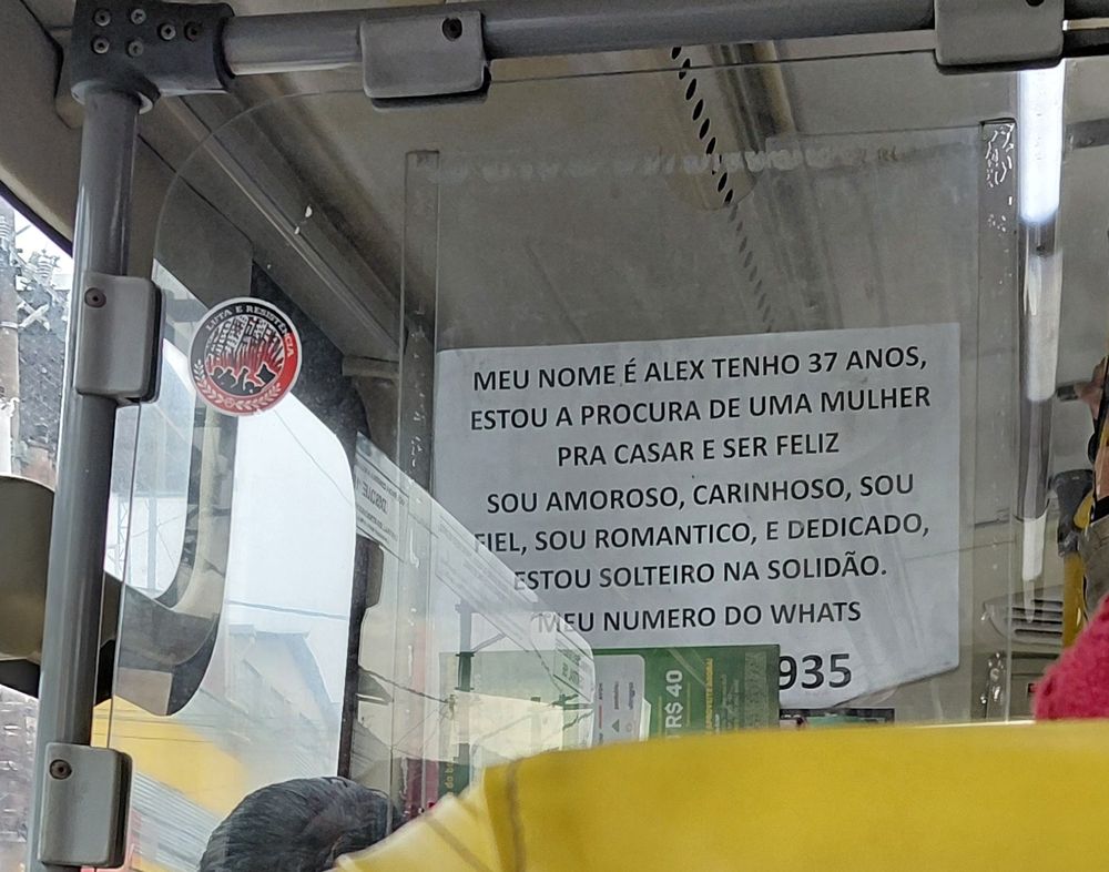 Anúncio em folha de sulfite dentro de um ônibus com os seguintes dizeres: Meu nome é Alex tenho 37 anos, estou a procura de uma mulher pra casar e ser feliz sou amoroso, carinhoso, sou fiel, sou romantico e dedicado, estou solteiro na solidão. Meu numero do whats ** ******935 