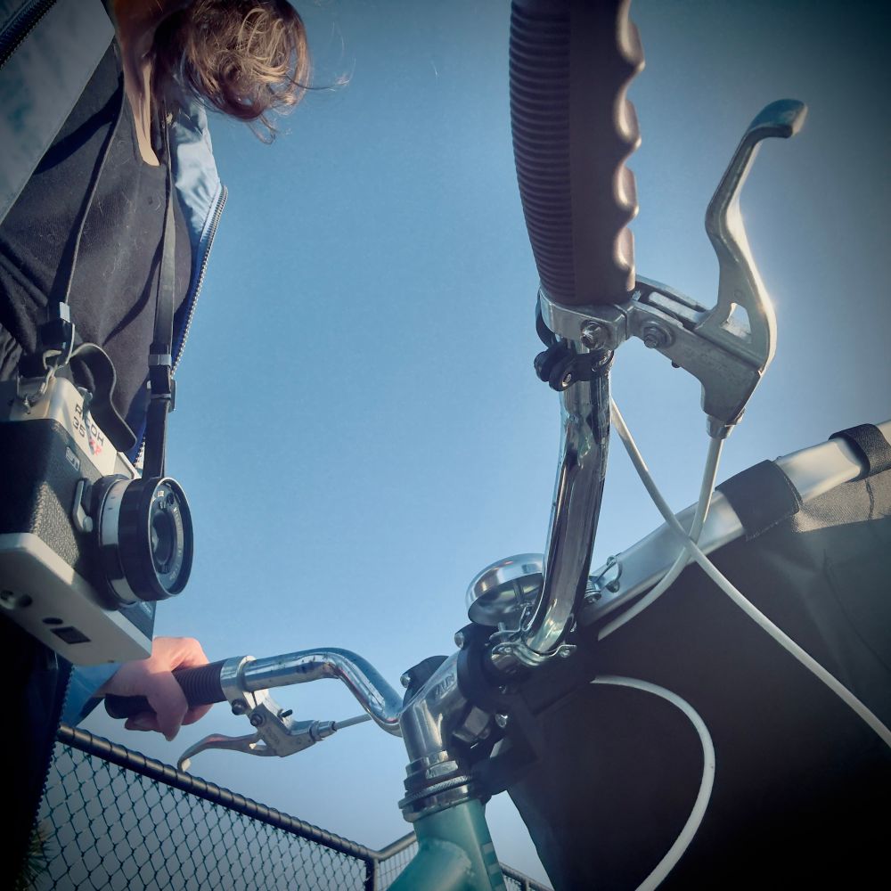 A look at handlebars and camera around neck, face obscured from view 