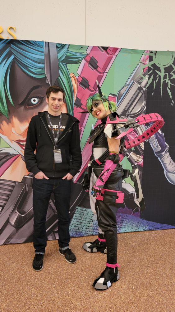 Photo of Ian standing next to a cosplayer of the Apex Legends character Alter.