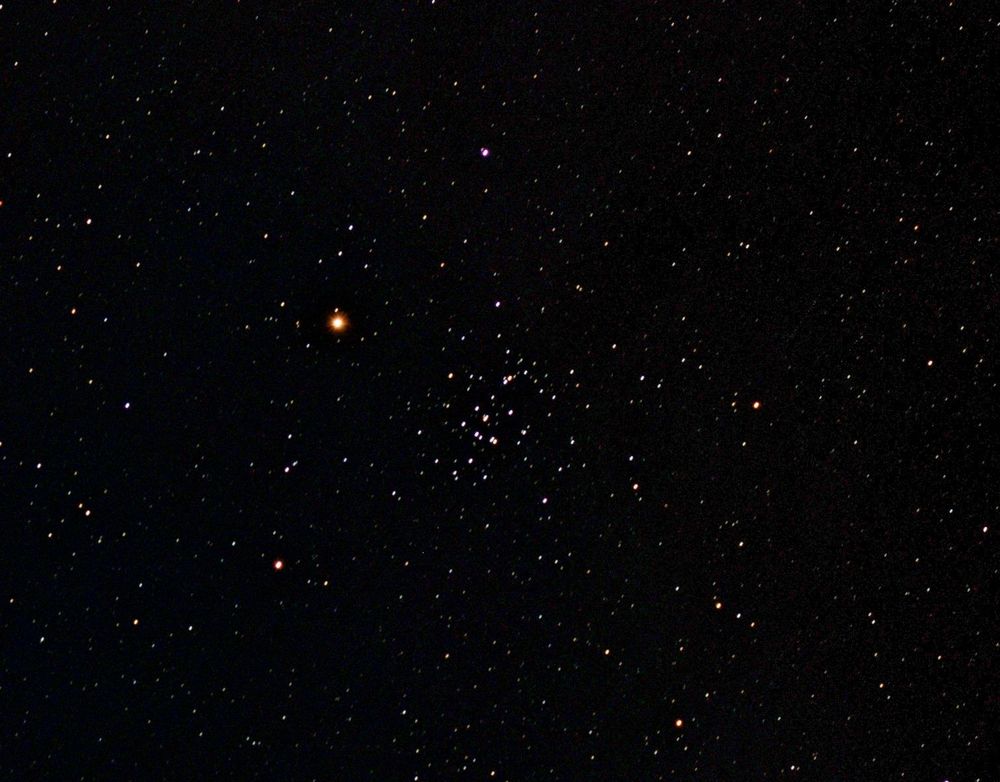 The Beehive cluster of stars at centre. Bright planet Mars to its left. Other fainter star dots on a dark background. 