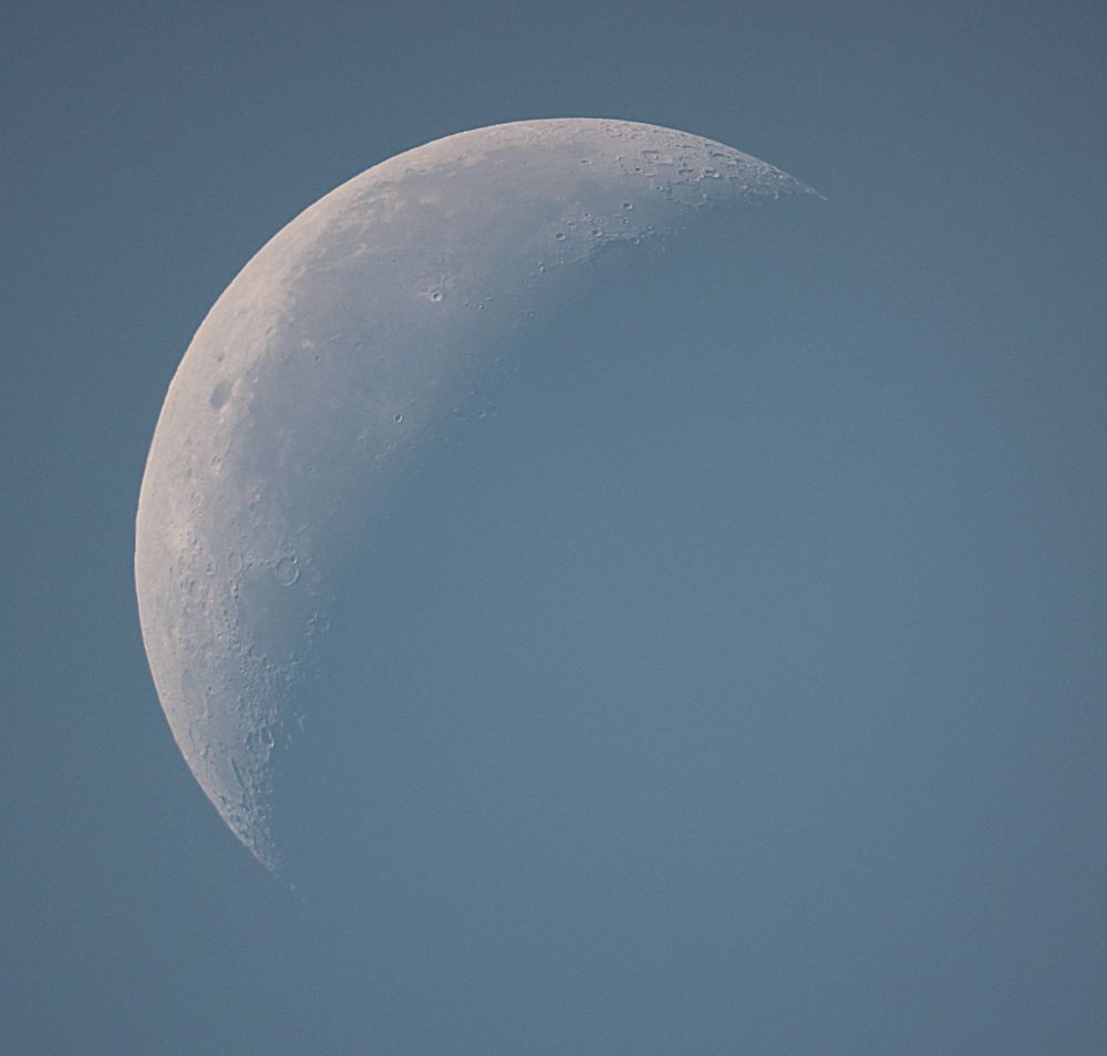The Moon at waning gibbous phase on a blue sky background. 