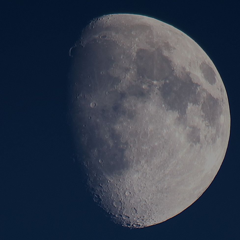 The Moon at waxing gibbous phase on a blue sky background. 