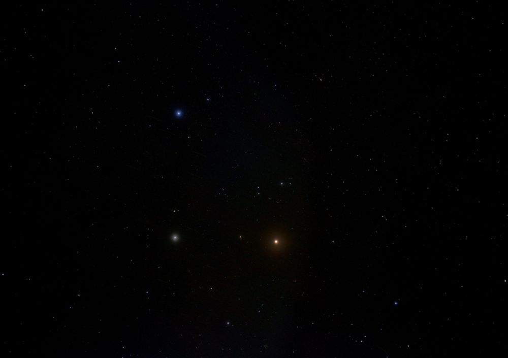 Planet Mars looking orange and bright below centre. Star Pollux to its left with the star Castor above. Numerous other star dots on a dark background. 