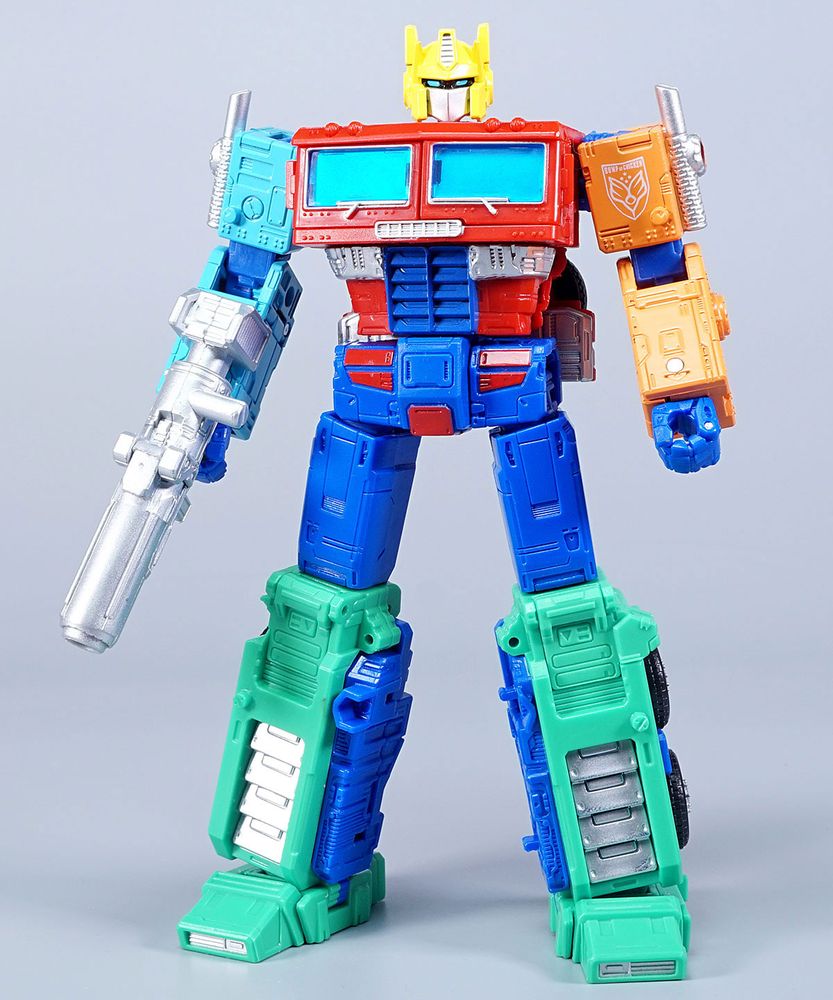 Bump of Chicken Convoy, a version of an Earthrise Optimus Prime cab in incredible colours.
Yellow head, with blue optics and silver faceplate.
Azure right arm, with indigo elbow and fist.
Red torso with silver stripe as normal, which makes the rest stand out. Grill is indigo instead of silver.
Peach left arm, with indigo elbow and fist.
Indigo pelvis and thighs, with red panels on the waist.
Turquoise lower legs and feet, with silver painted details.
Silver rifle and matching smokestacks.