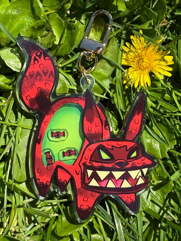 Sour macaraccoon shaker charm with three red sour candies inside a green belly. 