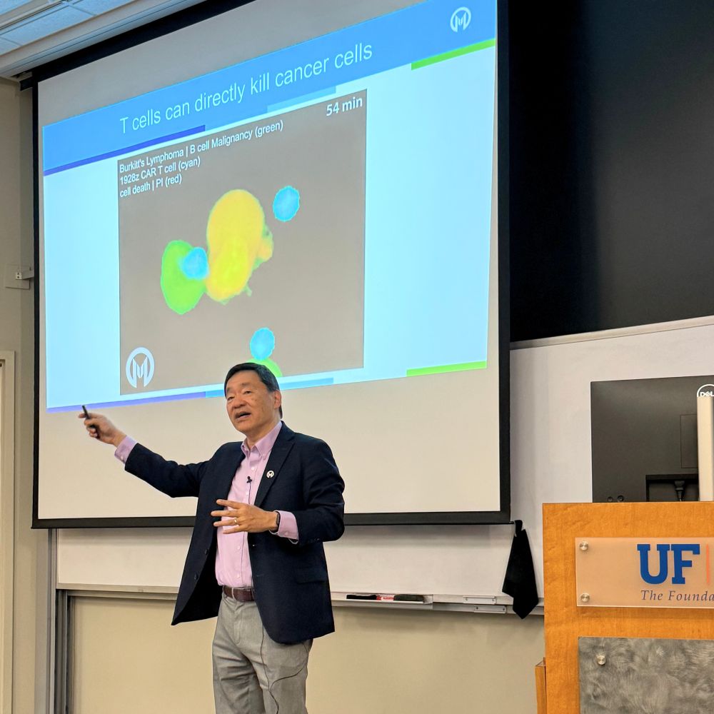 Dr. Hwu speaks in front of a slide.
