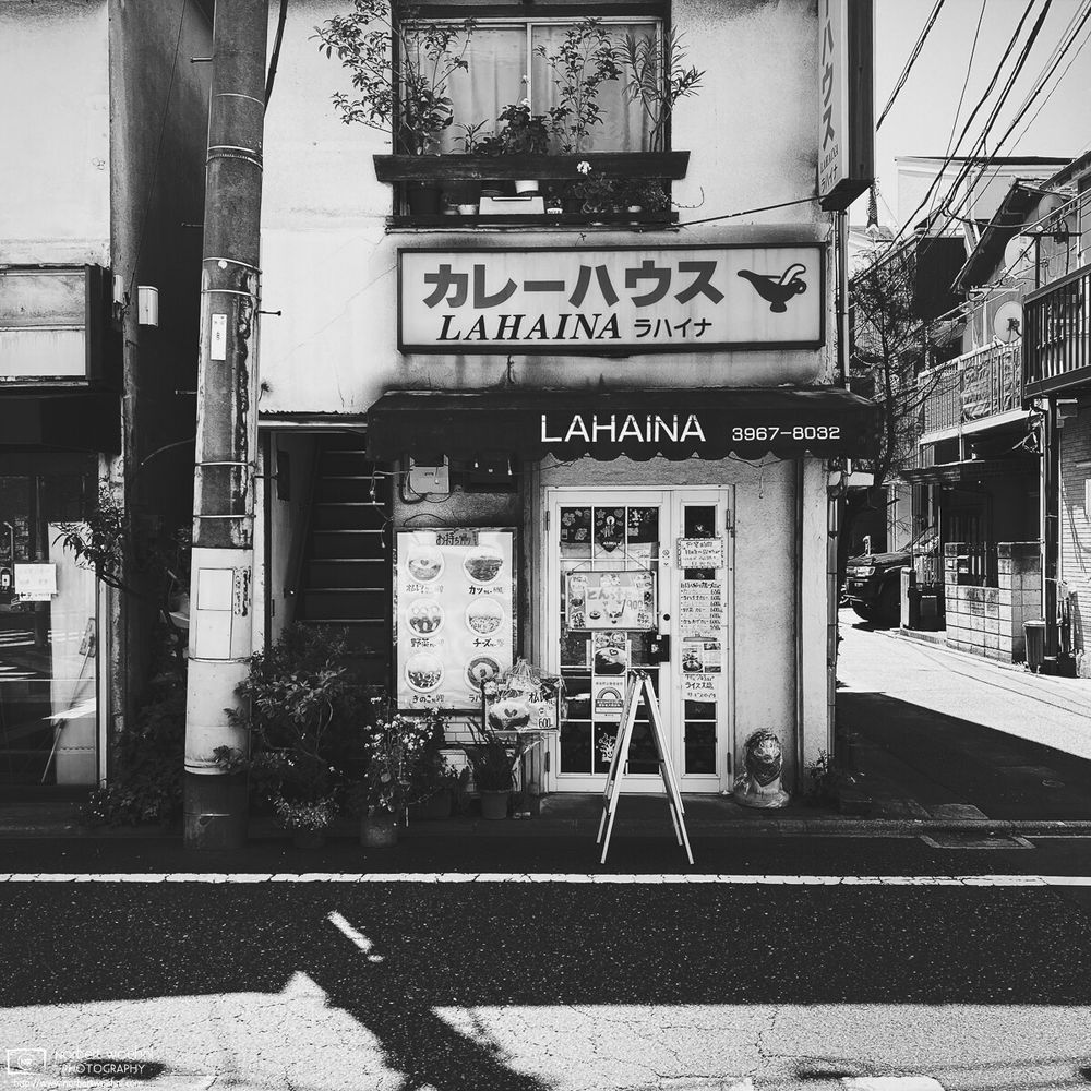 High-contrast monochrome photograph of "Curry House Lahaina", a small restaurant in the Azusawa neighborhood of Itabashi Ward in Tokyo, Japan.