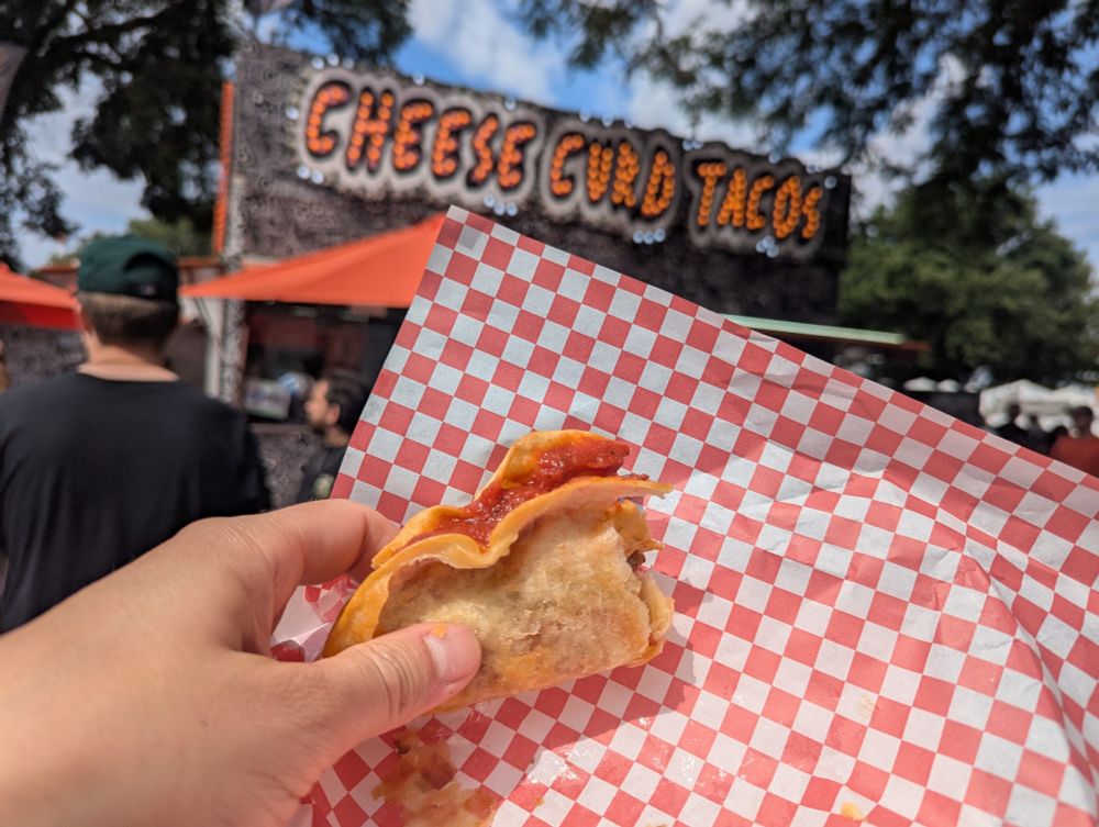 A taco in front of a cheese curd stand