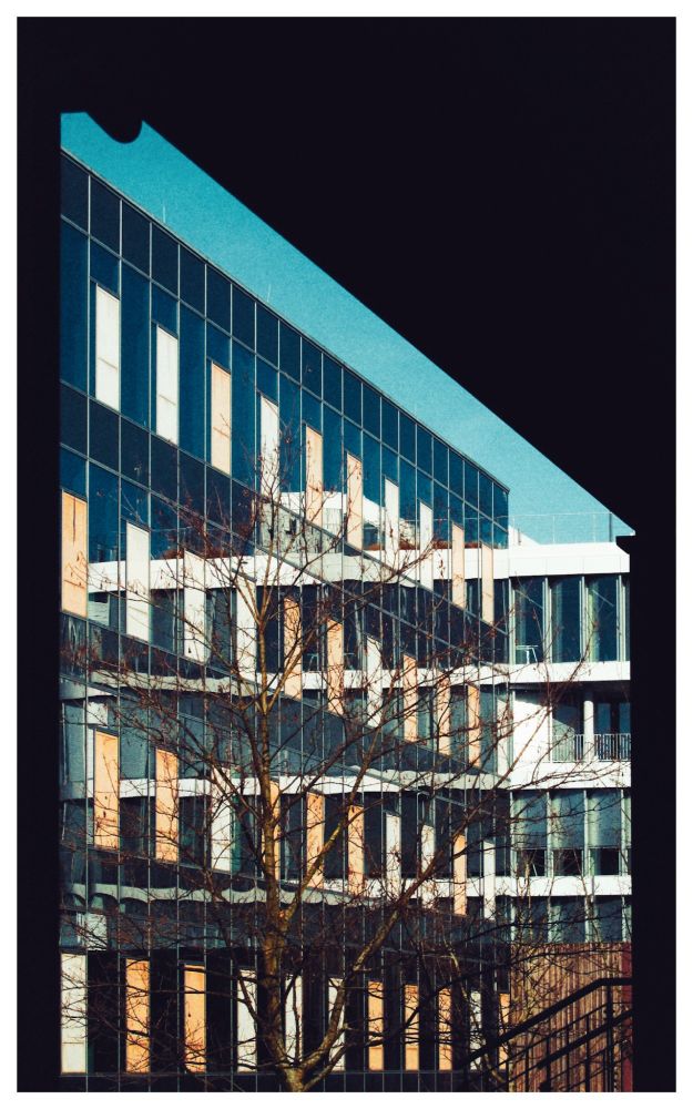 Zwei Bürogebäude nebeneinander,das rechte Gebäude spiegelt sich im linken,sodass es so aussieht als ginge es immer weiter 