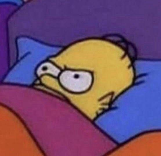 Homer Simpson laying in bed, covered up his nose with a blanket, with an annoyed expression