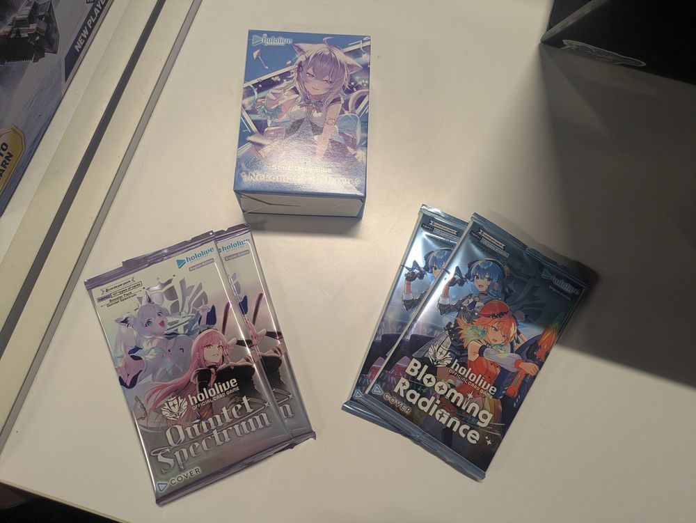 A Nekomata Okay starter deck, 2 card packs from the Blooming Radiance set and 2 card packs from the Quintet Spectrum set.
