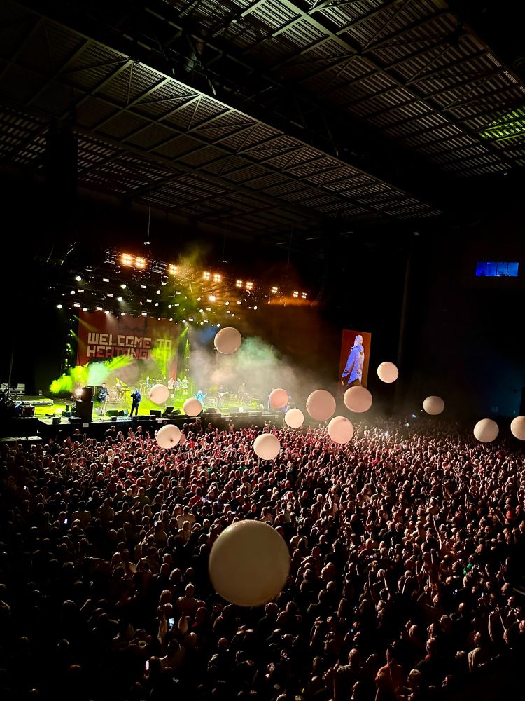 A wide shot of the stage at Leeds Arena showing the crowd with giant balloons bouncing around.