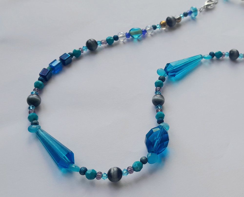 Necklace with mostly blue beads in different shapes and sizes.