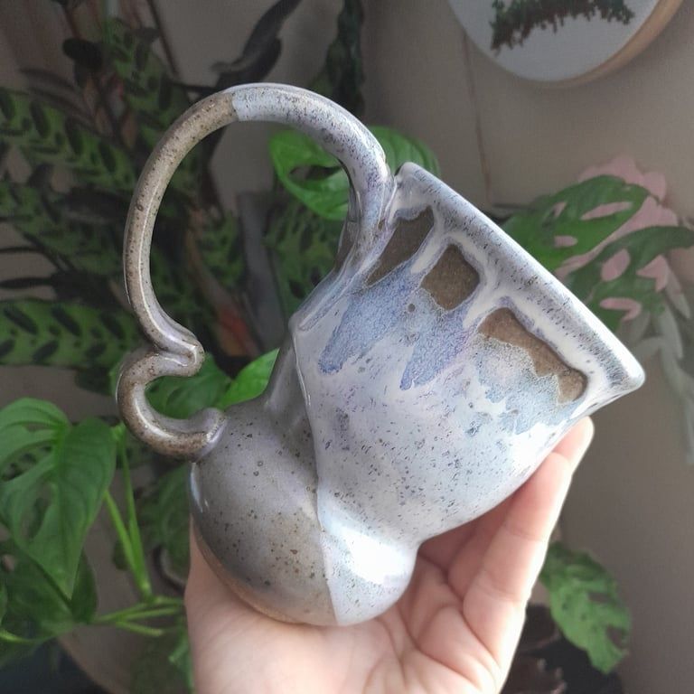 A whimsical mug with a drippy pale purple glaze and squiggly handle