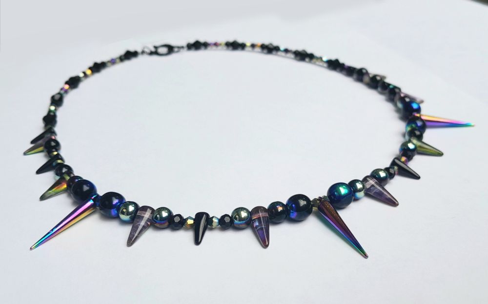 20" necklace with iridescent and black glass beads and spikes, rainbow metal spikes and a black-coloured toggle clasp.
