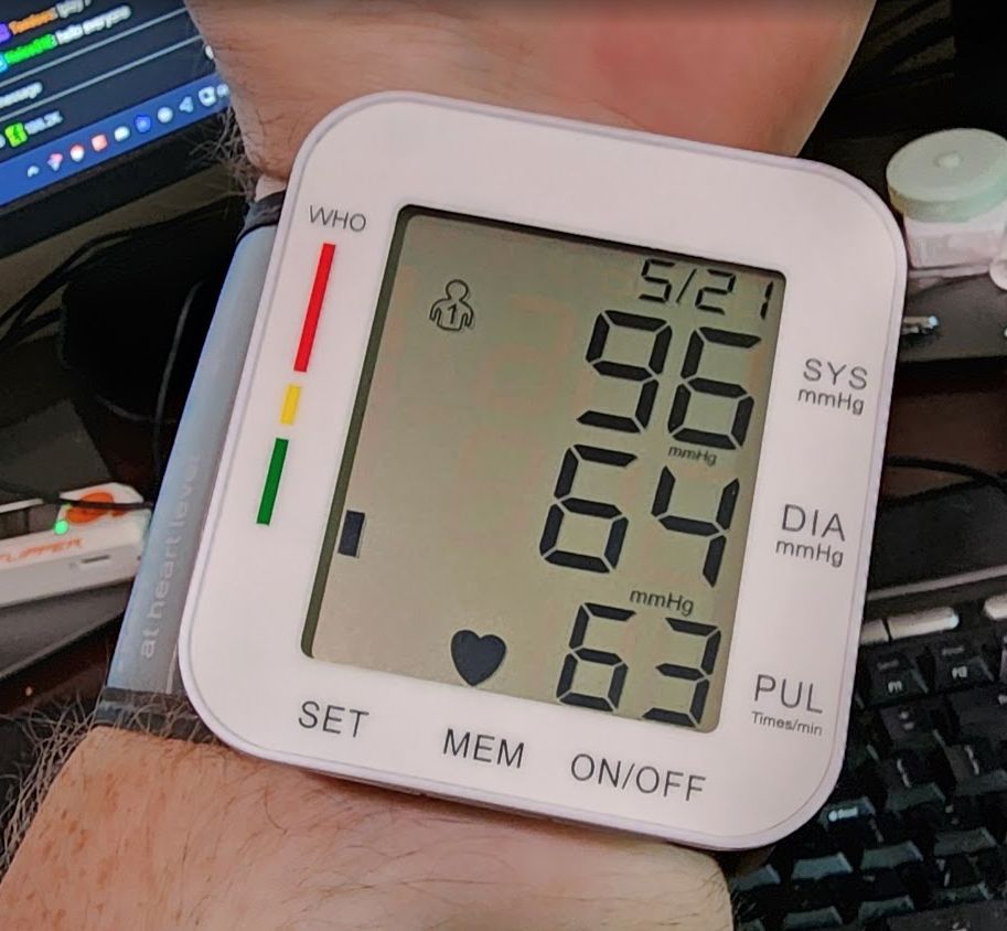 Blood pressure monitor showing a reading of 96/64 with a heart rate of 63 BPM.