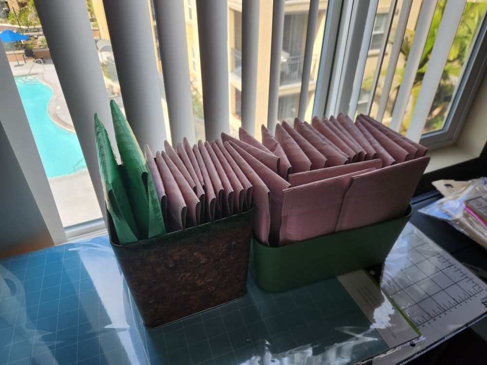 An image of a minecraft dirt block tin and green container containing around 40 small pink packages for pre orders