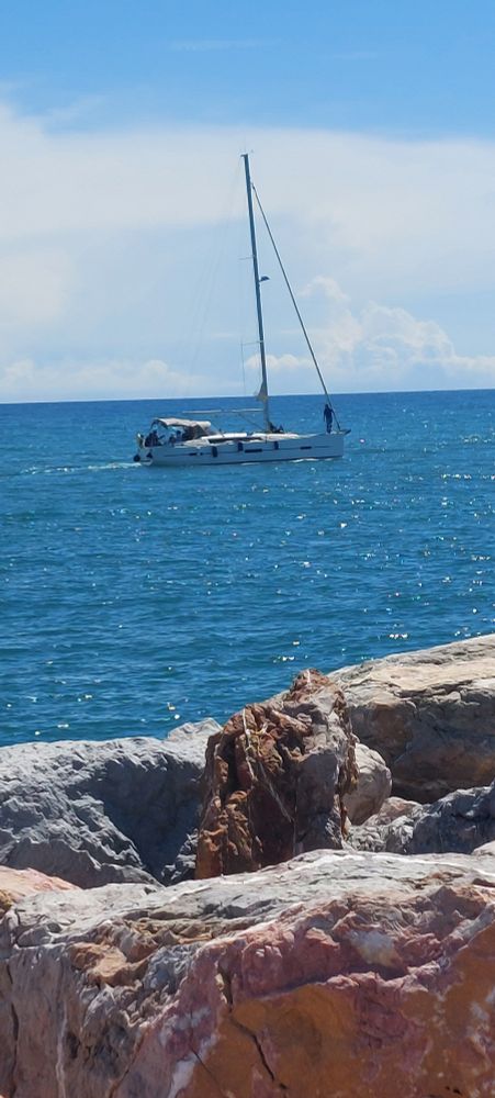 Un voilier sur une mer bleue et des rochers 