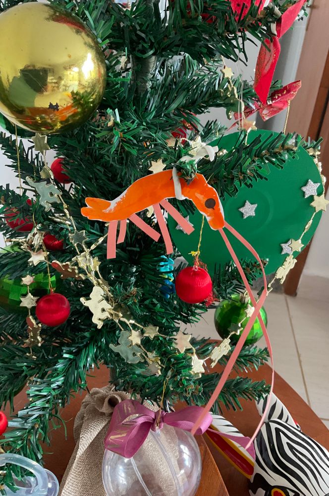 Foto de uma pequena árvore de Natal com um camarão de papel pendurado.