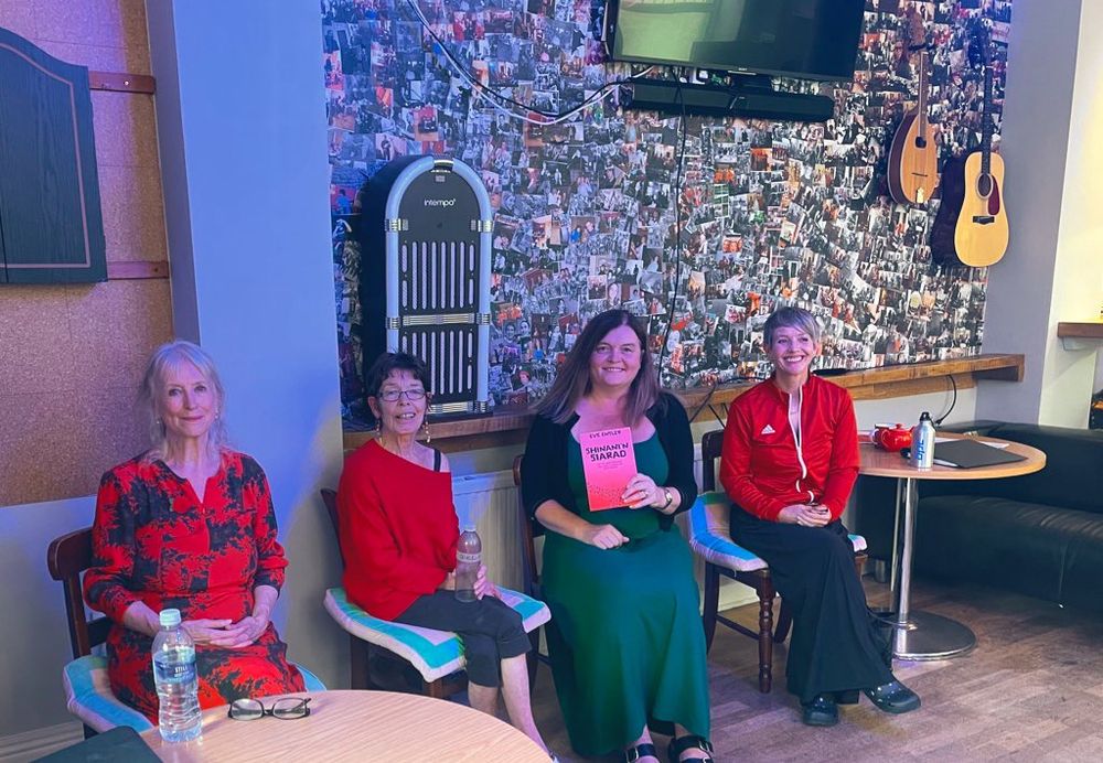 Sharon Morgan, Delyth Wyn and Maria Pride sitting with Sioned Williams MS who is holding a copy of Shinani’n Siarad.