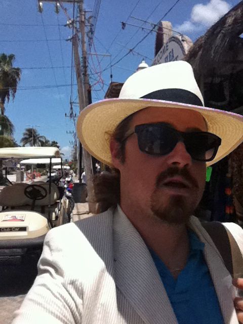 man with white wide brimmed hat in front of golf carts 