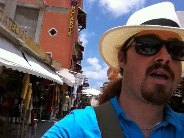 man in panama hat wanders street of small town 
