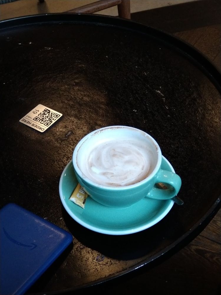 Eine türkise Tasse mit Chai Latte auf einem schwarzen Tisch 