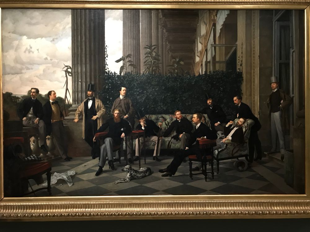 A group portrait of a Dalmatian and dozen or so white men standing and lounging under a monumental colonnade.