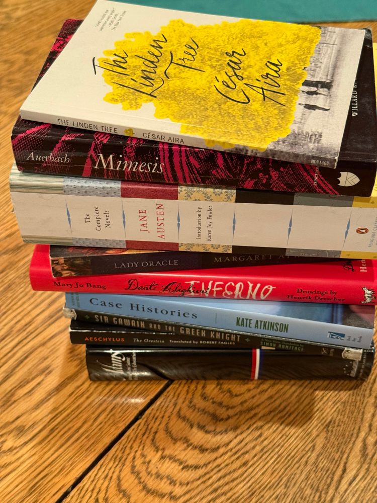A stack of books by authors whose last name begins with the letter "A", with César Aira's THE LINDEN TREE on top, with Auerbach's MIMESIS  below that, and next is THE COMPLETE NOVELS OF JANE AUSTEN.