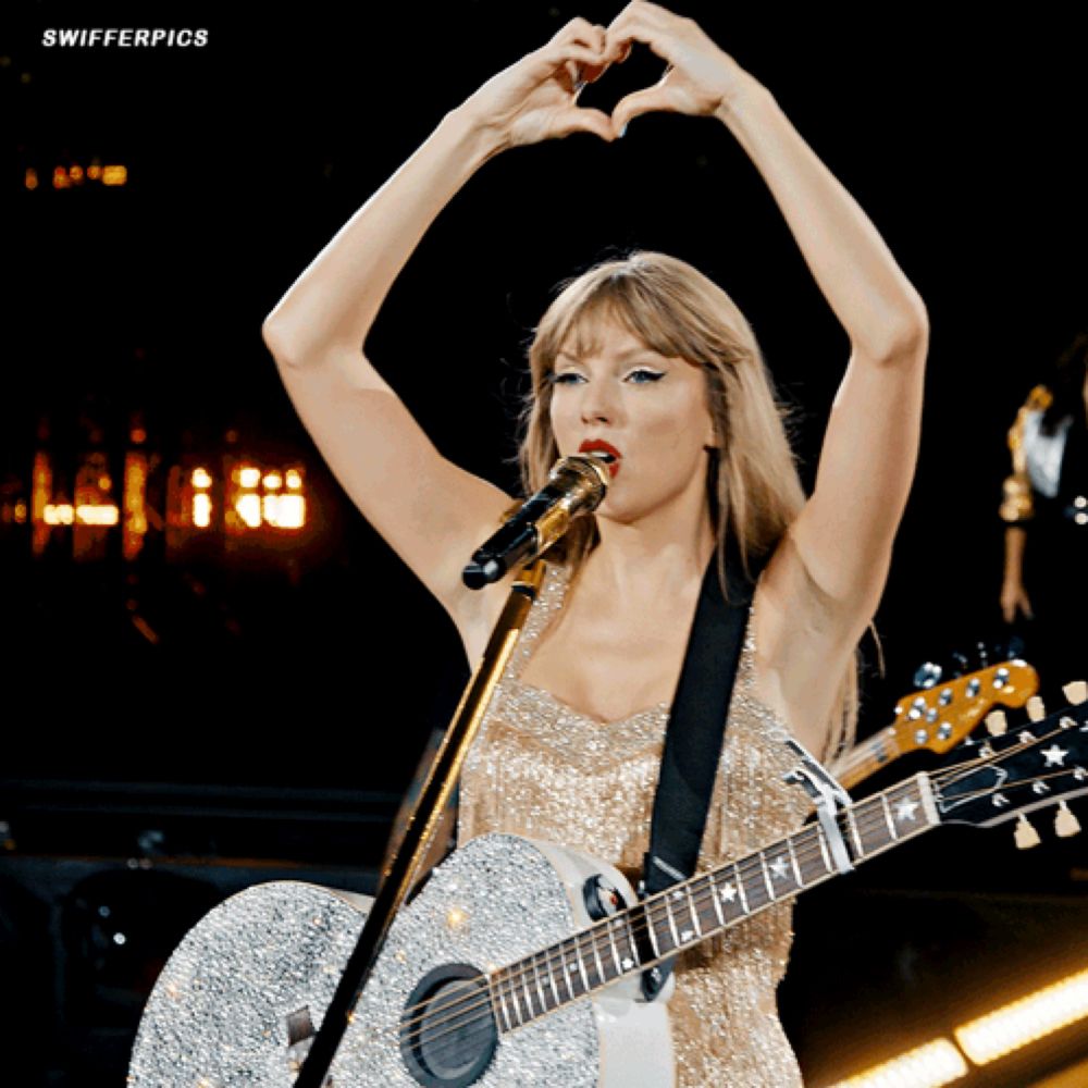 a woman holding a guitar and making a heart with her hands