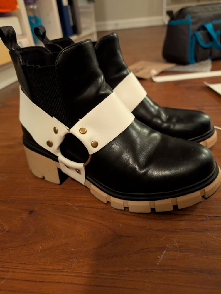 Black Chelsea boots with three white boot straps connected by two O-rings and rivets.