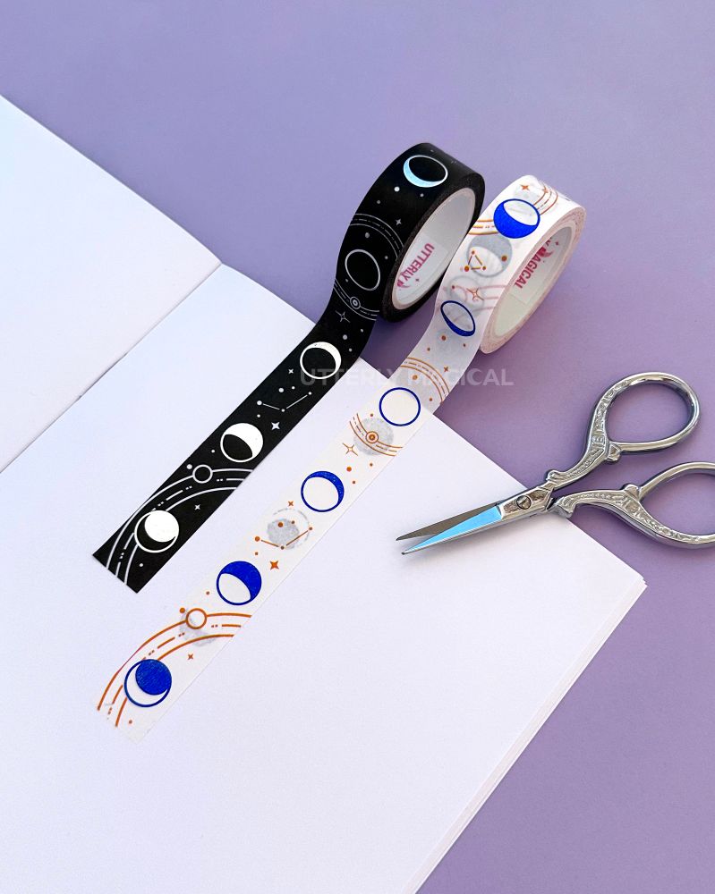 Two washi tapes on a notebook on a purple background with silver scissors next to it. 