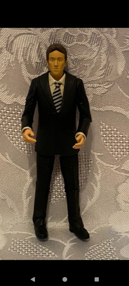 Plastic figure of a man in the black suit, white shirt and stripey blue and white tie.