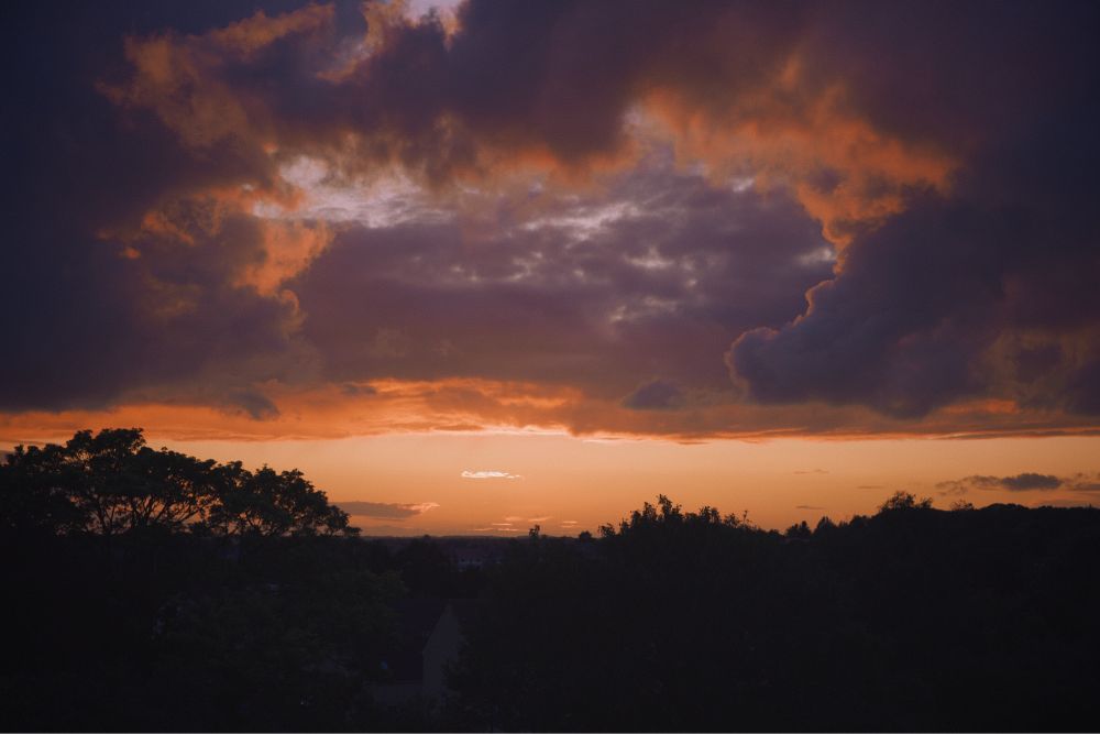 cloudy sunset with silhouettes of trees in foreground