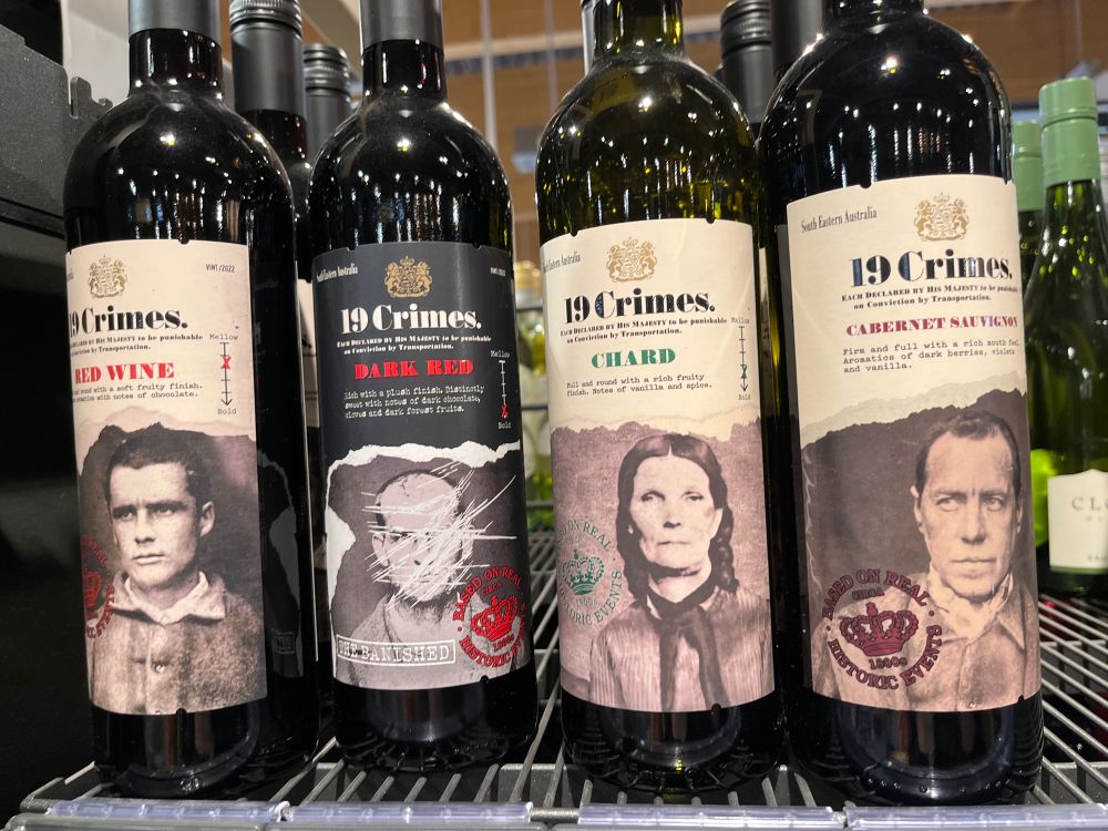 4 Weinflaschen von 19 Crimes, auf den Label sind schwarz-weiße Bilder von einzelnen Menschen zu sehen 