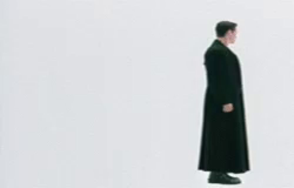 a man in a long black coat is standing in front of a large arrow .