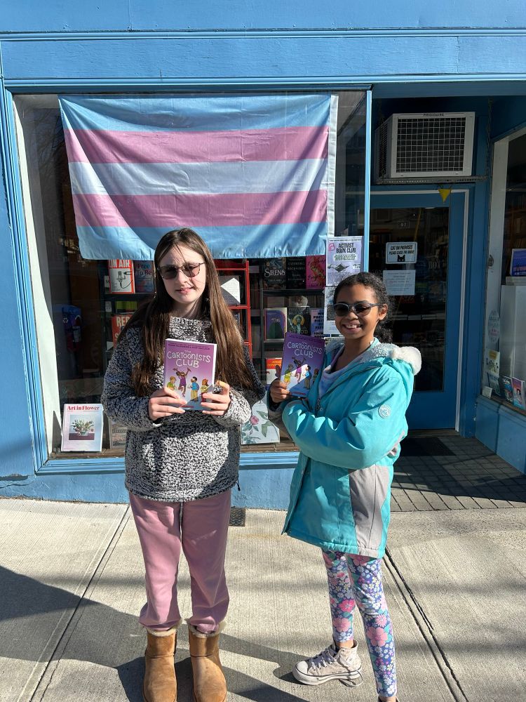 2 very happy girls holding copies of the new book The Cartoonists Club by Raina Telgemeier and Scott McCloud