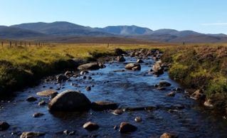 Photograph of upland salmon stream in Scotland looking up onto Loch Nagar mountain range. 