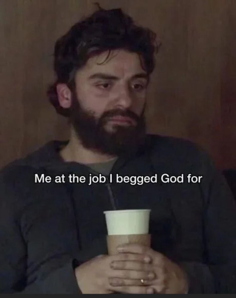 a very tired and disgruntled looking man holding a large coffee with the caption “me at the job I begged god for”