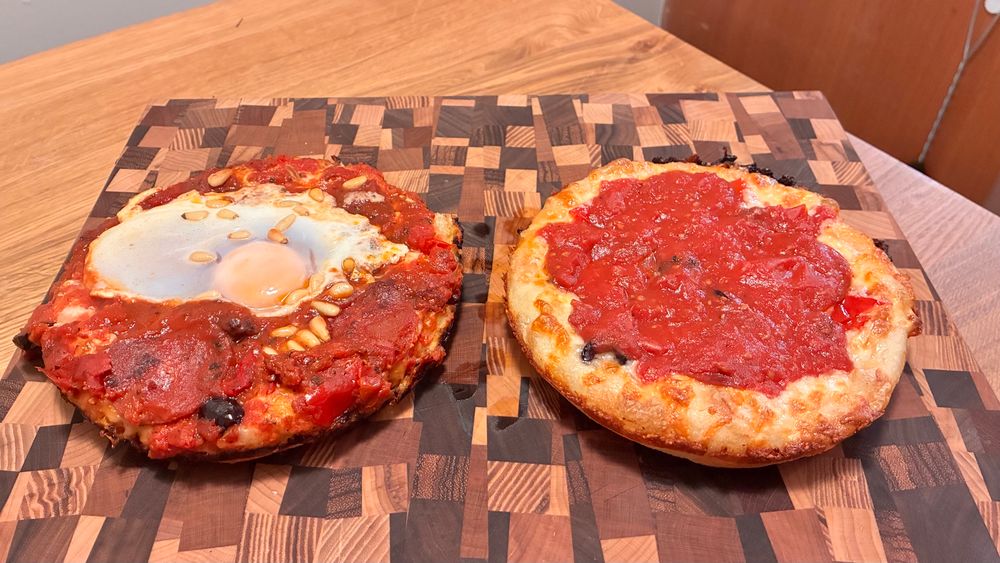 Two pizzas. One looks like a perfect red sauce pizza, the other looks like Picasso made pizza.