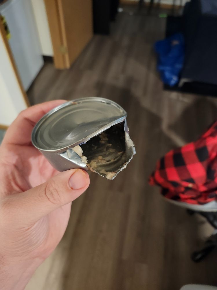 Me holding a tuna can with a gaping hole in the can