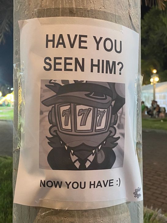 A printed poster of the Duck Shuffler affixed to a wooden pole. The sign reads: "HAVE YOU SEEN HIM?", then a drawing of the Duck Shuffler, then "NOW YOU HAVE :)" 
