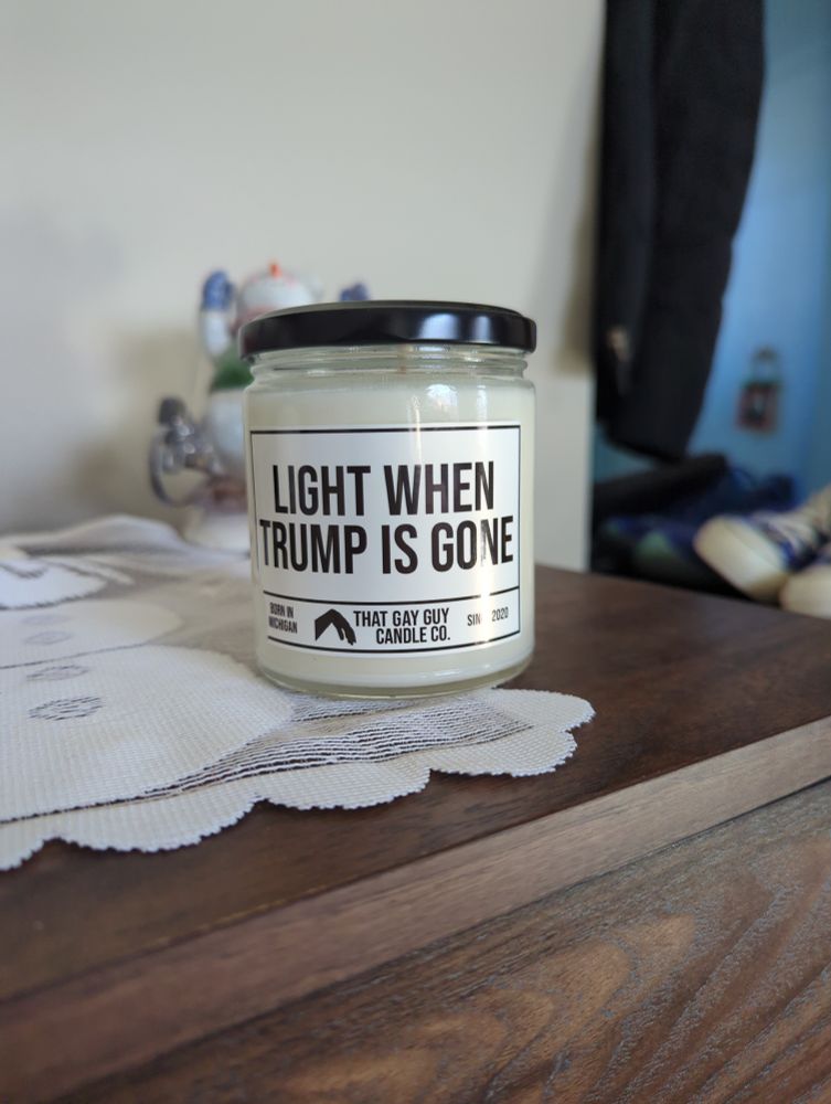 White candle in a jar with a black lid. The label says "LIGHT WHEN TRUMP IS GONE"