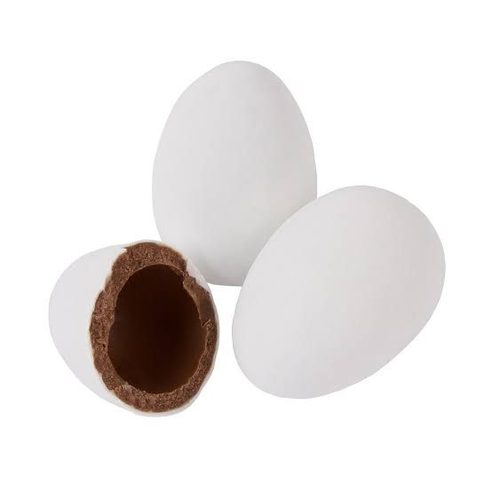 Close-up of white "hens' eggs" Easter chocolates, with one broken open so you can see the milk chocolate inside the hard white candy "shell".