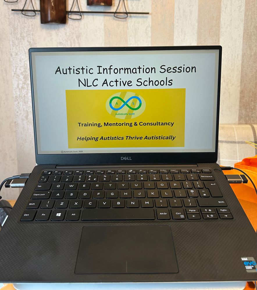 Picture of Scott’s laptop on a stand and desk. The PowerPoint cover slide with a beige colored background on the screen features texts that states:

Autistic Information Session

NLC Active Schools


Scott’s gold, blue and green Autistically Scott logo is displayed on a banner image on the slide. 

Training, Mentoring & Consultancy

Helping Autistics Thrive Autistically