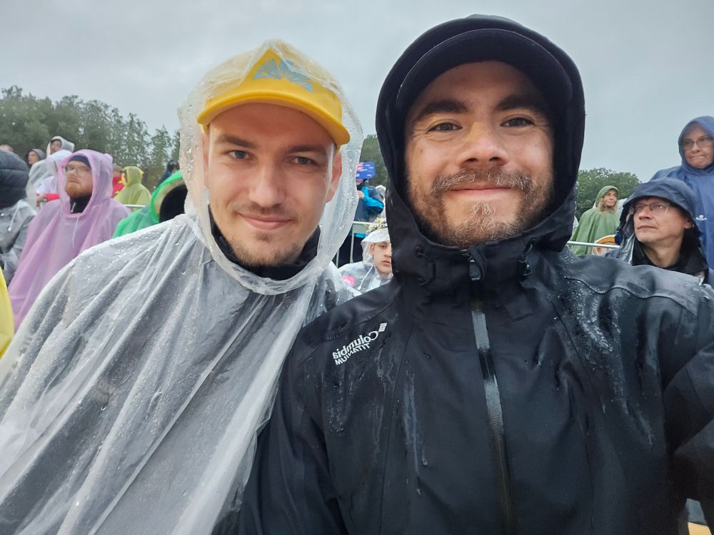 Two cute gays with raincoats on, drenched. 