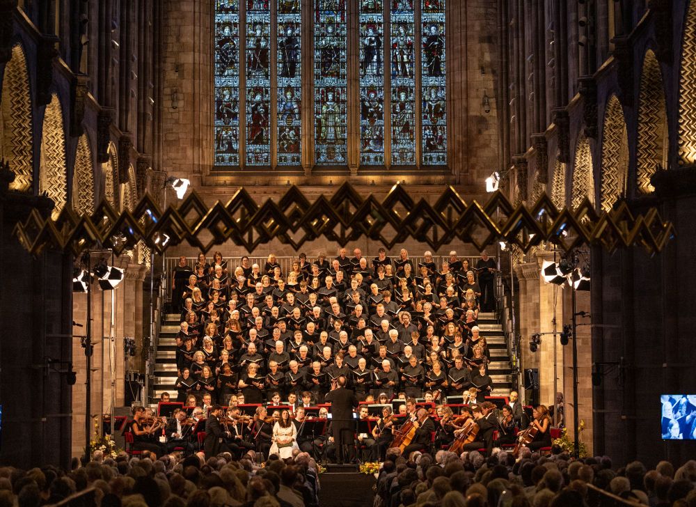 A photograph of a Three Choirs Festival Concert in Hereford Cathedral. A stage full of singers from the Festival Chorus and the Philharmonia Orchestra.