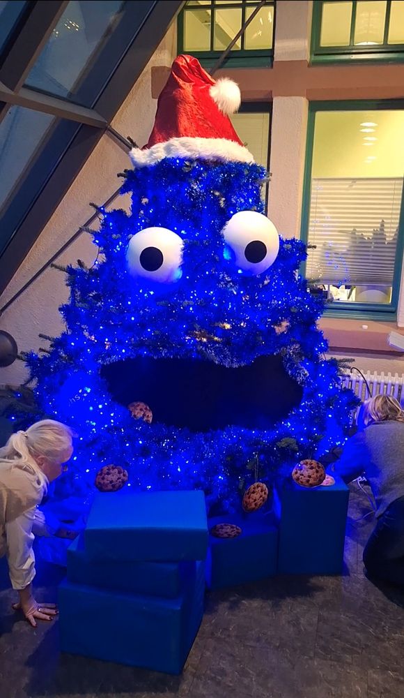 Der Weihnachtsbaum der Volkshochschule Wiesbaden ist über und über mit blauen Girlanden, zwei große Augen, einem riesigen Mund und einer großen Weihnachtsmütze geschmückt. Kekse hängen an den Zweigen, es ist das blaue Krümelmonster