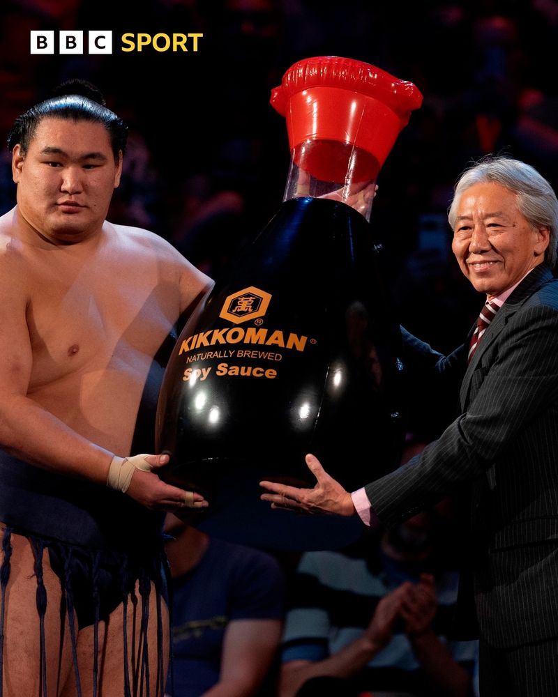 Image publiée par la BBC Sport montrant un champion de sumo honoré par une réplique géante de sauce soja : "Hoshoryu was gifted a giant soy sauce after becoming Grand Champion "