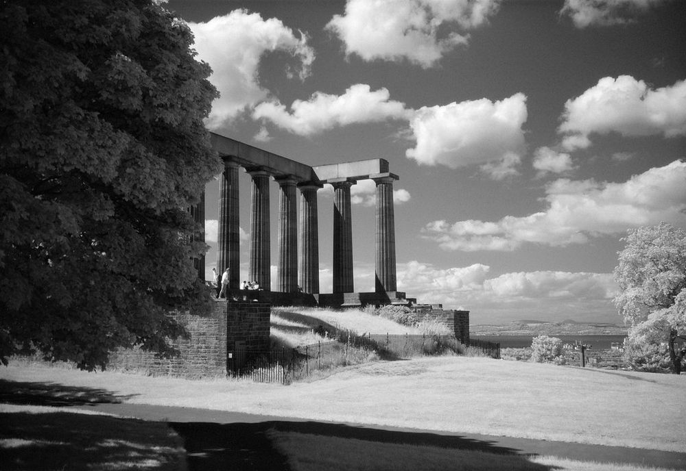 The back of the National Monument, the grass is almost white and the clouds are bright against the dark sky. 
